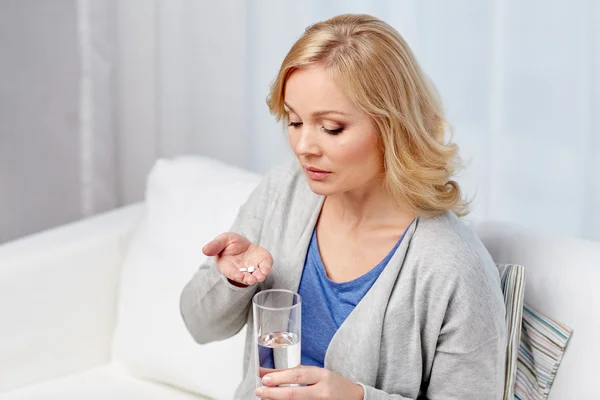 Vrouw met geneeskunde en waterglas thuis — Stockfoto