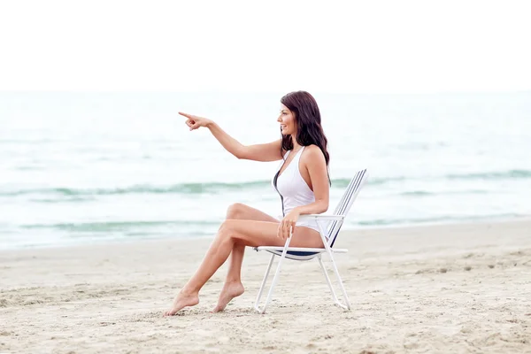 Smiling young woman sunbathing in lounge on beach — Stock Photo, Image