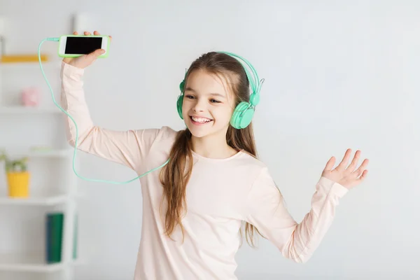 Jente med smarttelefon og hodetelefoner hjemme – stockfoto