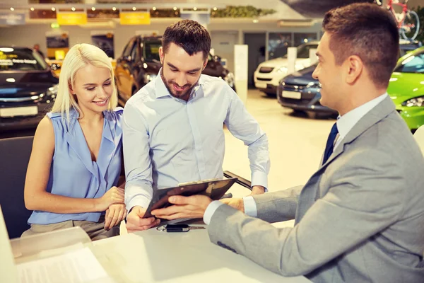 Couple heureux avec concessionnaire de voitures en salon ou salon de l'auto — Photo