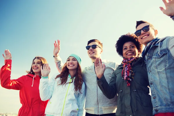 Happy teenage friends in shades waving hands — Stock Photo, Image