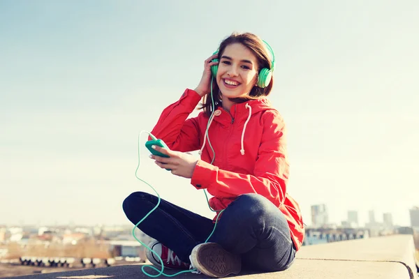 Feliz joven con teléfono inteligente y auriculares — Foto de Stock