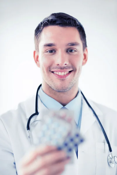 Junger männlicher Arzt mit Päckchen Pillen — Stockfoto