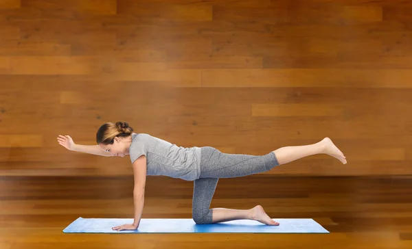 Wanita melakukan yoga dalam menyeimbangkan pose tabel di atas tikar — Stok Foto