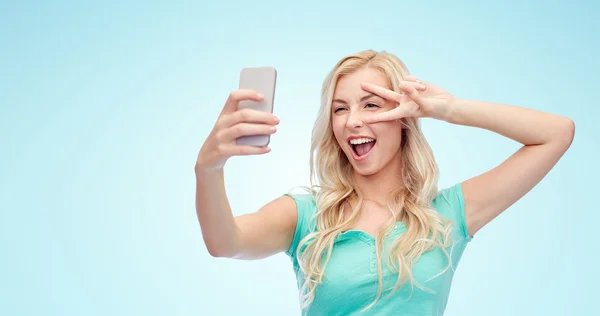 Smiling young woman taking selfie with smartphone — Stock Photo, Image