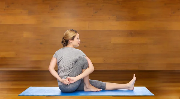 Женщина делает yoga в твист позе на циновке — стоковое фото