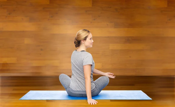 Женщина делает yoga в твист позе на циновке — стоковое фото