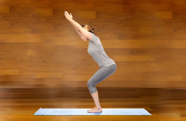 Femme faisant yoga dans la pose de chaise sur le tapis — Photo