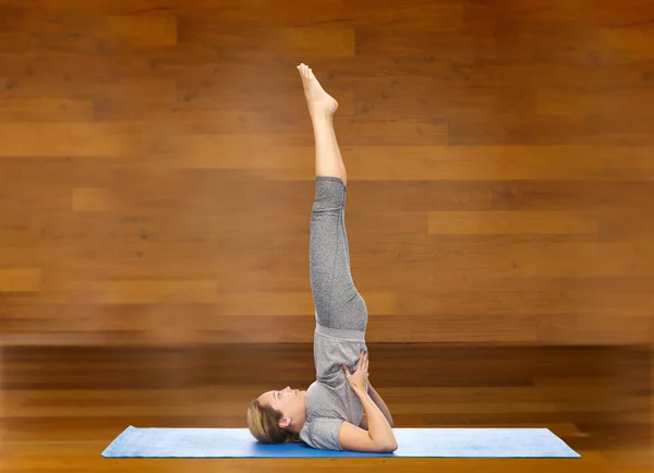 Woman making yoga in shoulder stand pose on mat — ストック写真