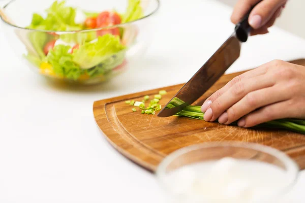 Close up van vrouw hakken groene ui met mes — Stockfoto