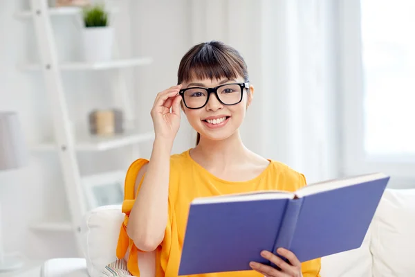 Sorridente giovane donna asiatica lettura libro a casa — Foto Stock