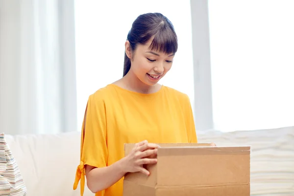 Glad asiatisk ung kvinna med paket låda hemma — Stockfoto
