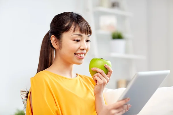 Feliz mujer asiática con tableta pc y manzana en casa — Foto de Stock