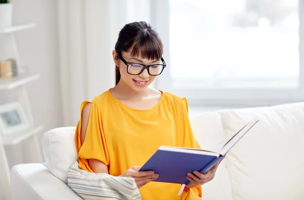 Jonge Aziatische vrouw leesboek thuis glimlachen — Stockfoto