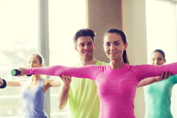 Grupo de personas sonrientes haciendo ejercicio con pesas —  Fotos de Stock