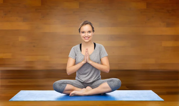 Mujer haciendo meditación de yoga en pose de loto en la estera — Foto de Stock