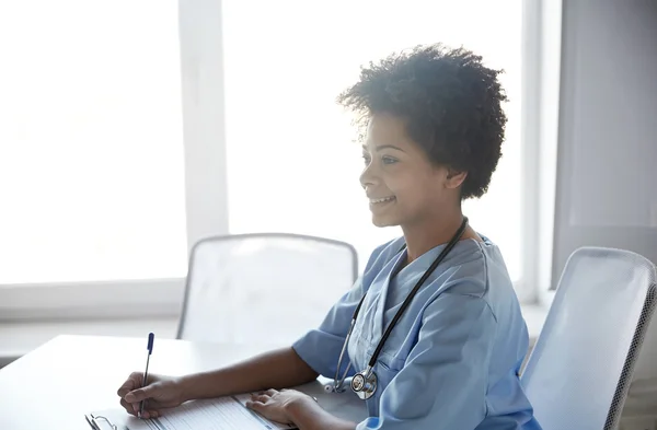 Médico ou enfermeira feliz escrevendo no hospital — Fotografia de Stock