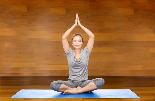 Donna che fa meditazione yoga in posa di loto sul tappeto — Foto Stock