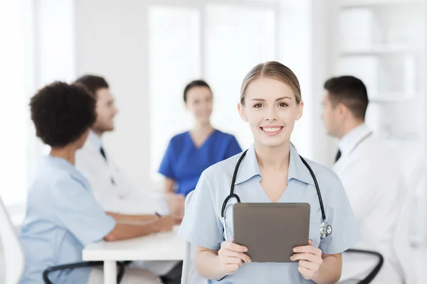 Zufriedener Arzt mit Tablet-PC über Team in Klinik — Stockfoto