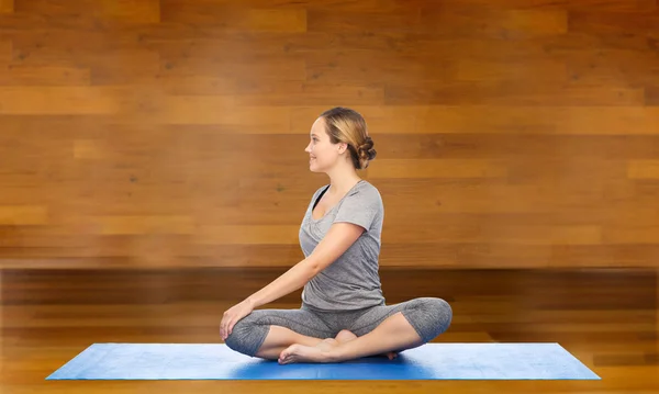 Vrouw maken yoga in twist pose op de mat — Stockfoto