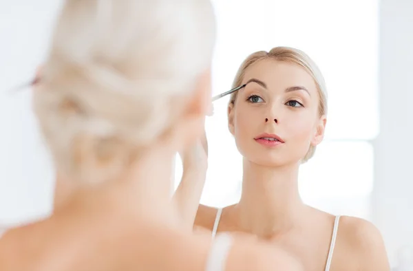 Kobieta z pędzla, robi makijaż brwi w łazience — Zdjęcie stockowe