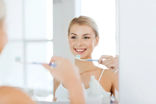 Mulher com escova de dentes limpeza dentes no banheiro — Fotografia de Stock