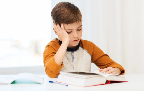 Student pojke läsa bok eller lärobok hemma — Stockfoto