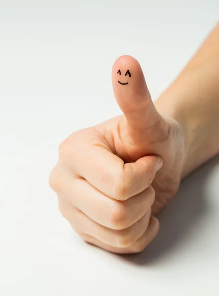 Primer plano de la mano mostrando el pulgar con la cara sonriente —  Fotos de Stock