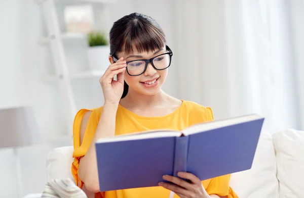 Smiling young asian woman reading book at home — Stock Photo, Image