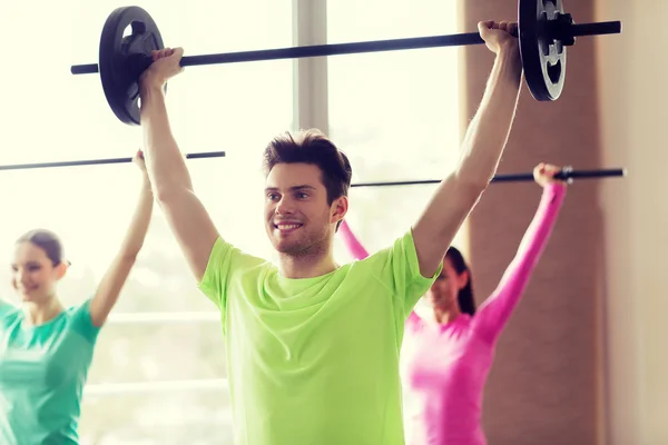 Grupo de personas haciendo ejercicio con barra de pesas en el gimnasio — Foto de Stock