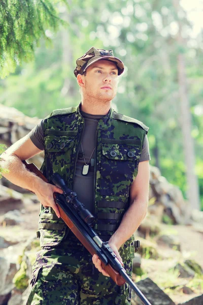 Young soldier or hunter with gun in forest — Stock Photo, Image