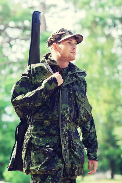 Young soldier or hunter with gun in forest — Stock Photo, Image