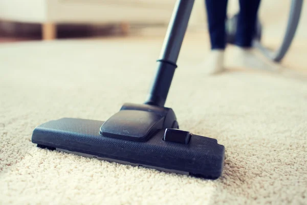 close up of woman legs with vacuum cleaner at home