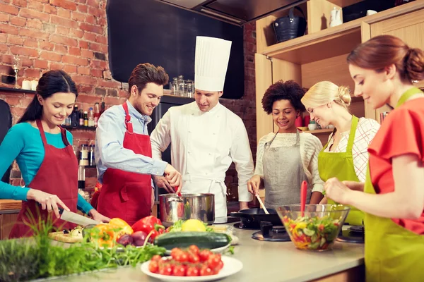 Amigos felizes e cozinheiro chef cozinhar na cozinha — Fotografia de Stock