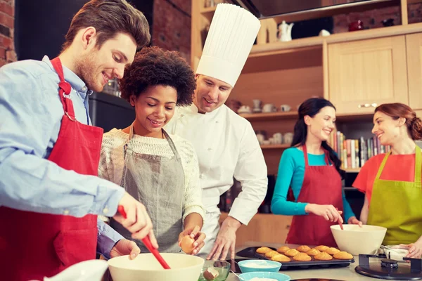 Glückliche Freunde und Koch backen in der Küche — Stockfoto