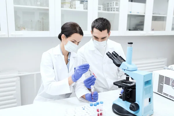 Jovens cientistas que fazem testes ou pesquisas em laboratório — Fotografia de Stock