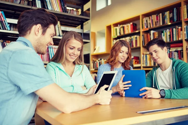 Alunos felizes com tablet pc na biblioteca — Fotografia de Stock