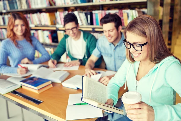 Estudantes lendo e bebendo café na biblioteca — Fotografia de Stock