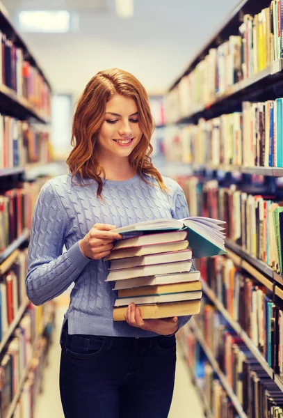 Menina estudante feliz ou mulher com livros na biblioteca — Fotografia de Stock