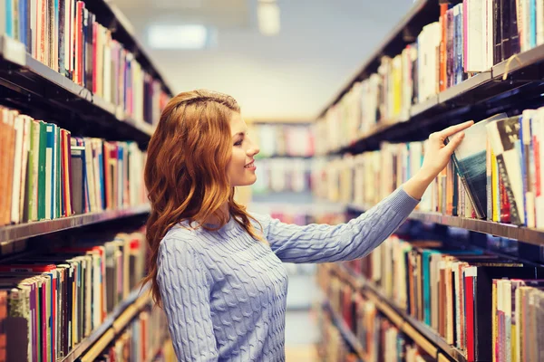 Menina estudante feliz ou mulher com livro na biblioteca — Fotografia de Stock