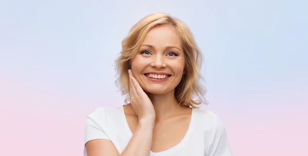 Lachende vrouw in wit t-shirt haar gezicht aan te raken — Stockfoto