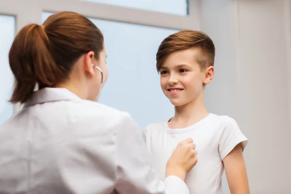 Médico con estetoscopio escuchando a un niño feliz — Foto de Stock