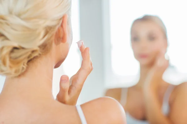 Close up de mulher aplicando creme facial no banheiro — Fotografia de Stock