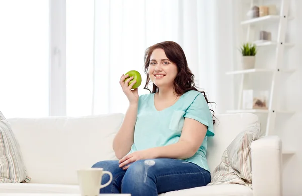 Ευτυχισμένος συν μέγεθος γυναίκα τρώει πράσινο μήλο στο σπίτι — Φωτογραφία Αρχείου