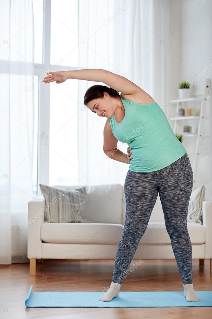 Plus size woman on mat at home Stock Photo by ©Syda_Productions 104442812