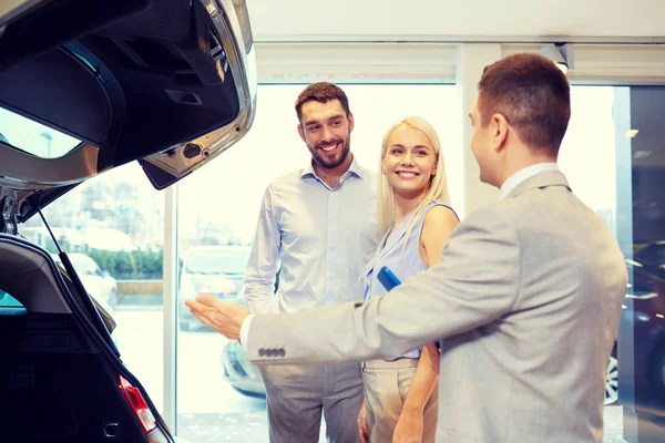 Glückliches Paar mit Autohändler in Auto-Show oder Salon — Stockfoto