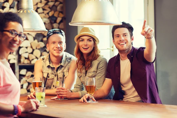 Glückliche Freunde mit Getränken, die mit dem Finger auf die Bar zeigen — Stockfoto