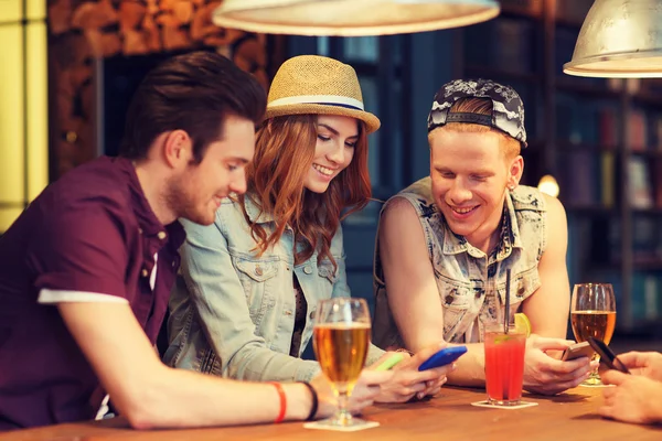 Amis heureux avec smartphones et boissons au bar — Photo