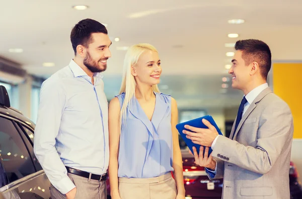 Happy couple with car dealer in auto show or salon — Stock Photo, Image