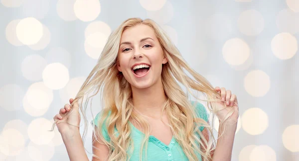 Sonriente joven mujer sosteniendo su hebra de pelo —  Fotos de Stock